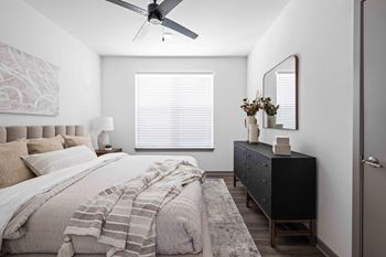 A bedroom with a bed, dresser, and a ceiling fan at The Quinn Luxury Apartments, Pensacola, FL, 32526